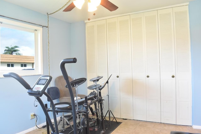 exercise area with ceiling fan and light tile patterned floors