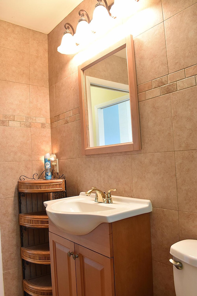 bathroom with tile walls, toilet, and vanity