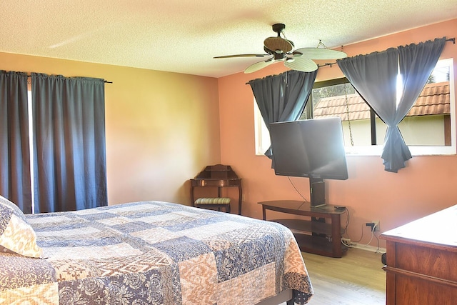 bedroom with ceiling fan, light wood-type flooring, and a textured ceiling