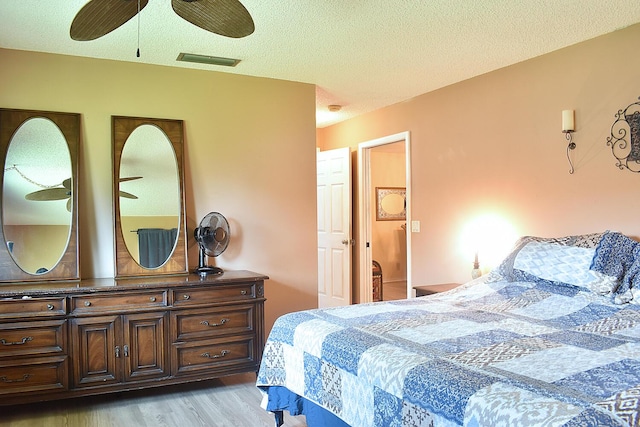 bedroom with a textured ceiling, ceiling fan, and light hardwood / wood-style flooring