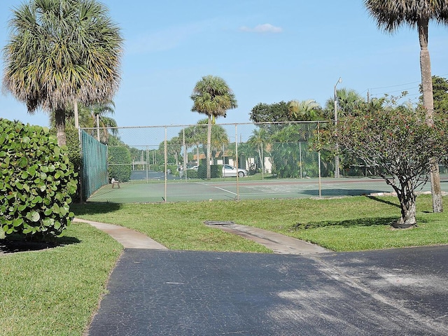 view of community with tennis court and a lawn