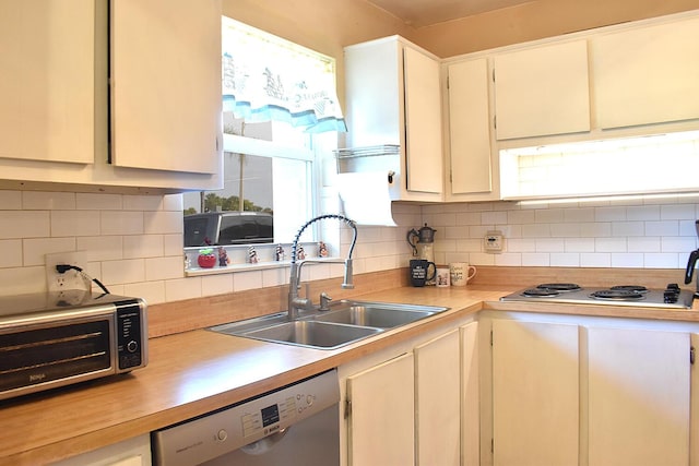 kitchen featuring cooktop, dishwasher, backsplash, and sink