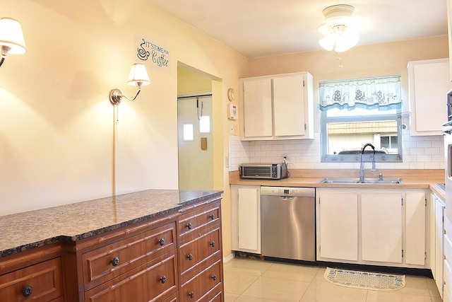 kitchen featuring white cabinetry, light tile patterned flooring, a wealth of natural light, stainless steel dishwasher, and sink