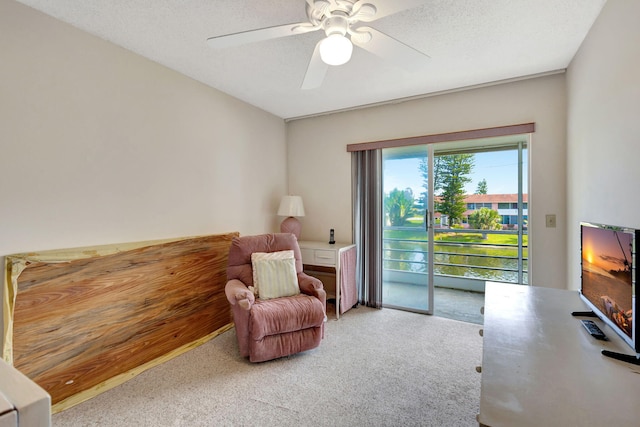 sitting room with ceiling fan, carpet, and a textured ceiling