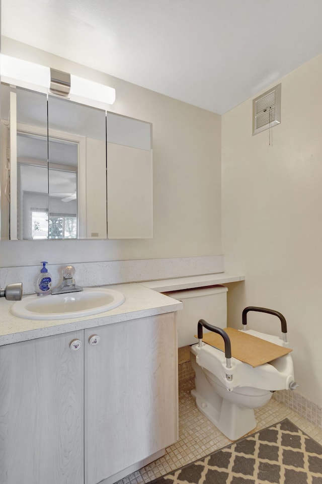 bathroom with toilet, vanity, and tile patterned flooring