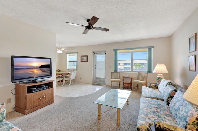 living room with ceiling fan, light colored carpet, and a textured ceiling