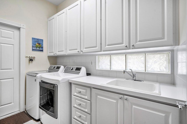 clothes washing area featuring cabinets, sink, and washing machine and dryer