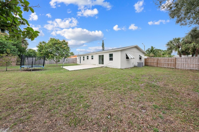 rear view of house featuring central AC, a patio, a yard, and a trampoline