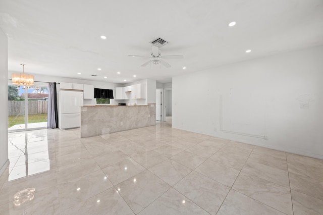 unfurnished living room with ceiling fan with notable chandelier