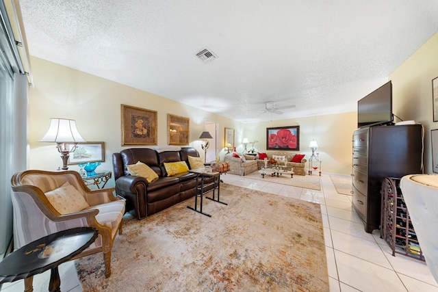 living room with ceiling fan, a textured ceiling, and light tile patterned floors