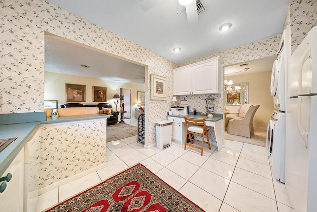 kitchen with ceiling fan, light tile patterned floors, stacked washer and dryer, white cabinets, and white refrigerator