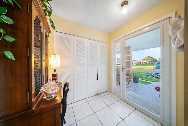 tiled entryway with a textured ceiling