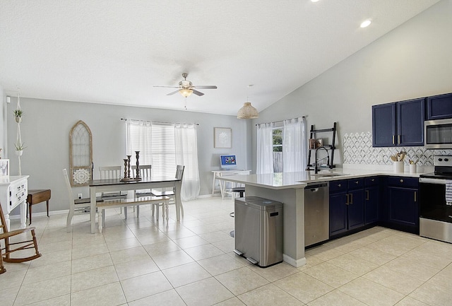 kitchen with blue cabinets, stainless steel appliances, kitchen peninsula, and tasteful backsplash