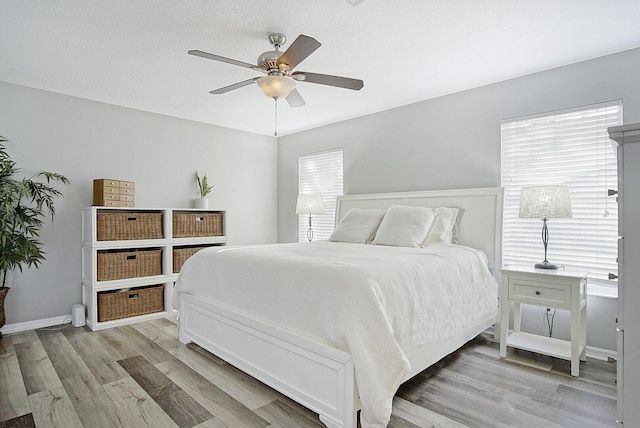 bedroom with ceiling fan, light hardwood / wood-style flooring, and multiple windows