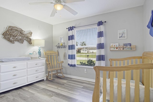 bedroom with ceiling fan, light wood-type flooring, and a crib