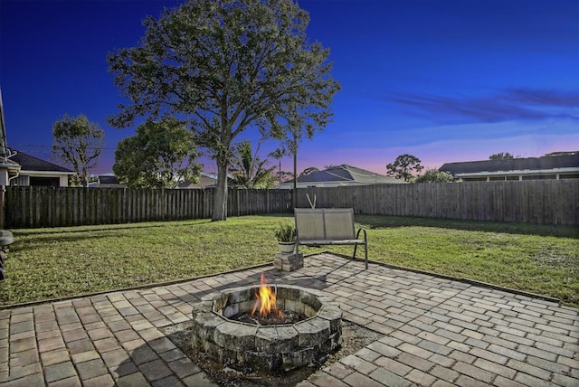 patio terrace at dusk with a fire pit and a lawn