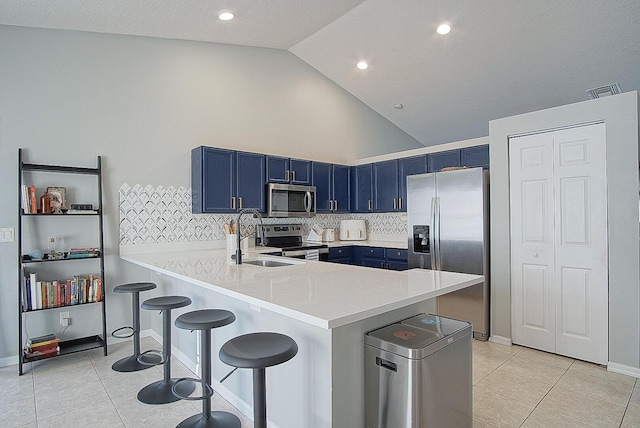 kitchen with kitchen peninsula, a kitchen breakfast bar, blue cabinetry, light tile patterned floors, and stainless steel appliances