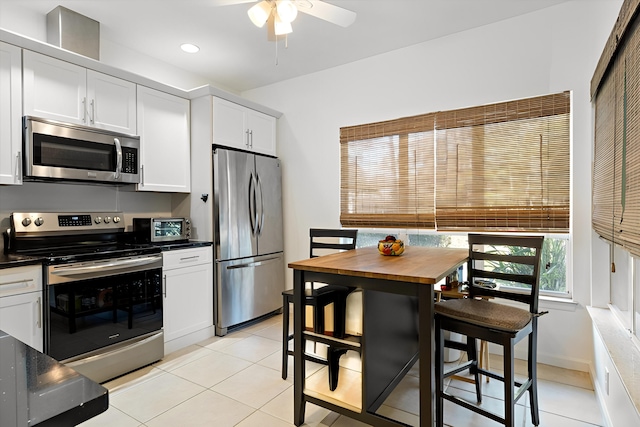 kitchen with stainless steel appliances, light tile patterned flooring, white cabinetry, and recessed lighting