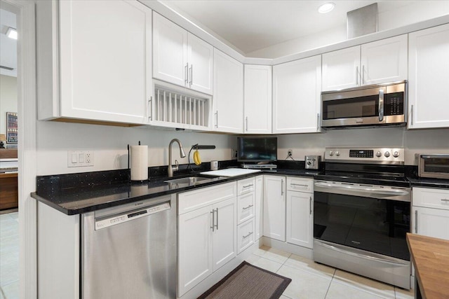 kitchen with light tile patterned floors, a toaster, a sink, white cabinetry, and appliances with stainless steel finishes