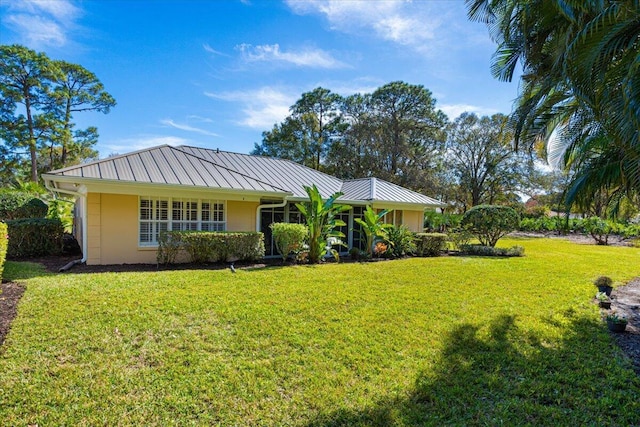 view of front of house featuring a standing seam roof, metal roof, stucco siding, and a front yard