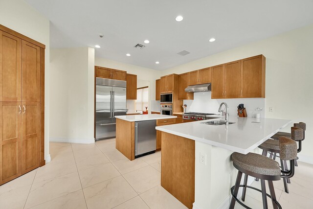 kitchen featuring sink, built in appliances, a kitchen breakfast bar, and kitchen peninsula