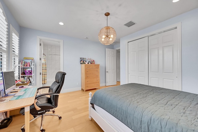 bedroom featuring an inviting chandelier, light hardwood / wood-style flooring, and a closet