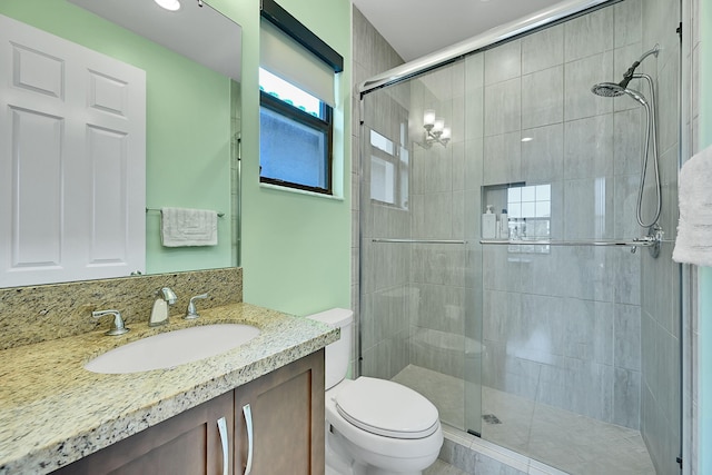 bathroom with vanity, a shower with shower door, and toilet