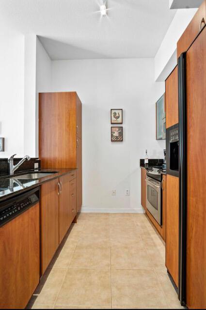 kitchen featuring paneled built in fridge, stainless steel range, sink, and light tile patterned flooring