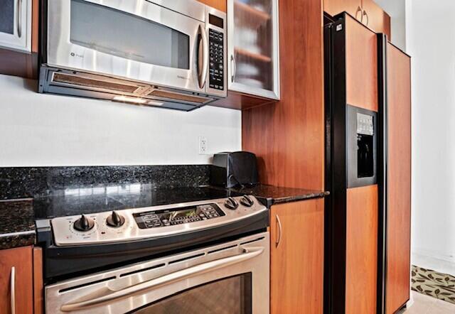 kitchen with stainless steel appliances, tile patterned flooring, and dark stone counters