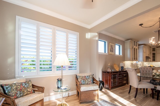 living area with light wood-type flooring, a wealth of natural light, crown molding, and a notable chandelier