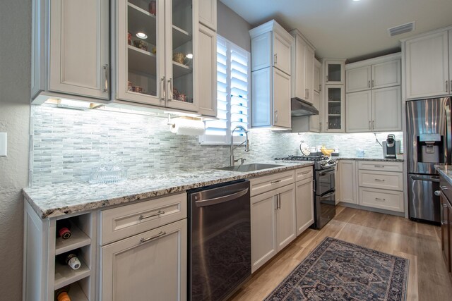 kitchen with light hardwood / wood-style flooring, appliances with stainless steel finishes, sink, white cabinets, and light stone counters