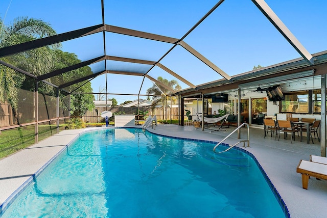 view of swimming pool featuring ceiling fan, glass enclosure, and a patio