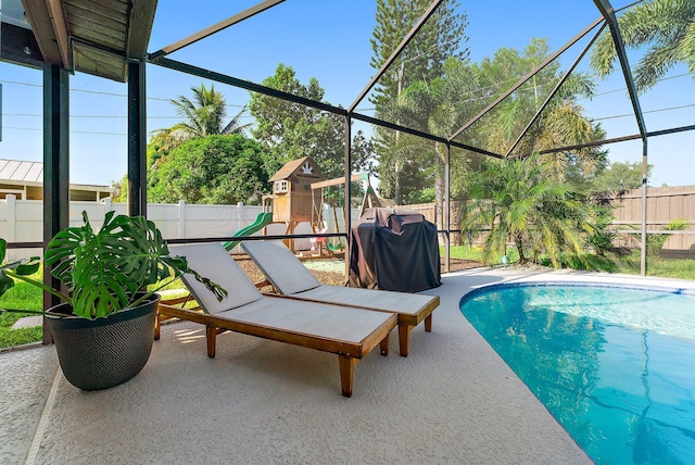 view of pool with glass enclosure, a fenced backyard, and a patio