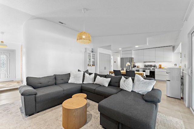 living room with vaulted ceiling, light tile patterned flooring, visible vents, and recessed lighting