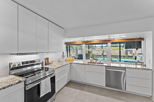 kitchen with stainless steel appliances, white cabinets, a sink, and modern cabinets