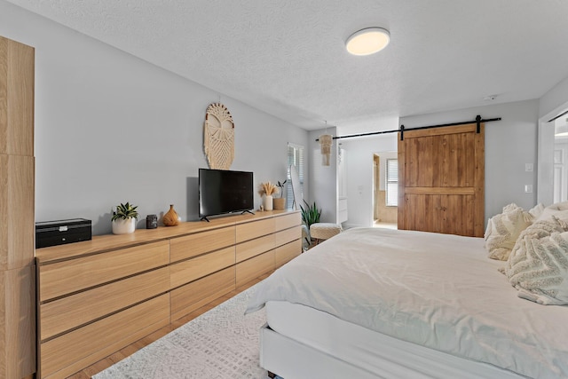 bedroom with a barn door and a textured ceiling