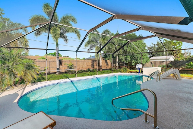 view of swimming pool featuring a patio, a lanai, and a shed