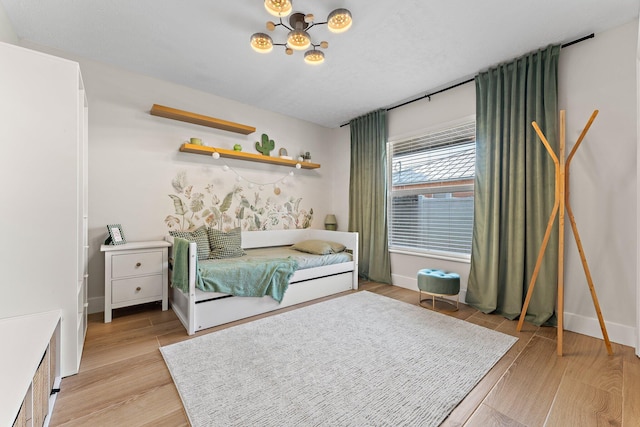 bedroom with light wood-style flooring, a chandelier, and baseboards