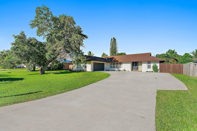 ranch-style house with an attached garage, driveway, fence, and a front lawn