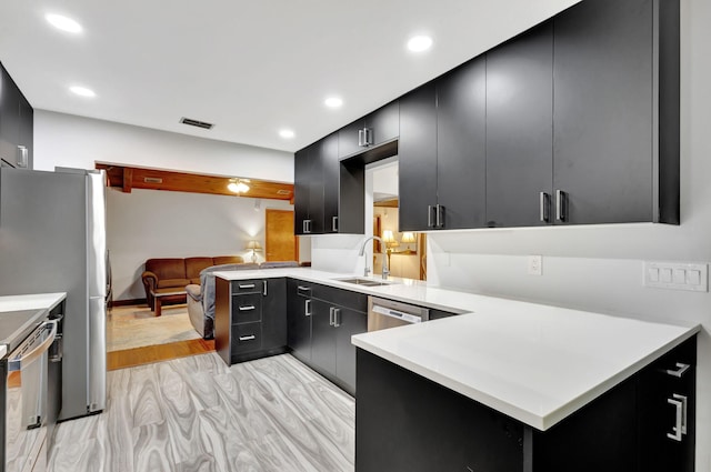 kitchen with appliances with stainless steel finishes, light hardwood / wood-style floors, kitchen peninsula, and sink