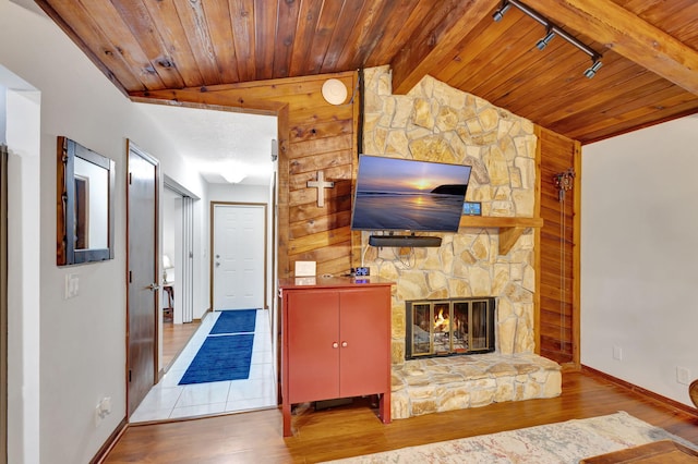 unfurnished living room featuring hardwood / wood-style floors, lofted ceiling with beams, and a stone fireplace