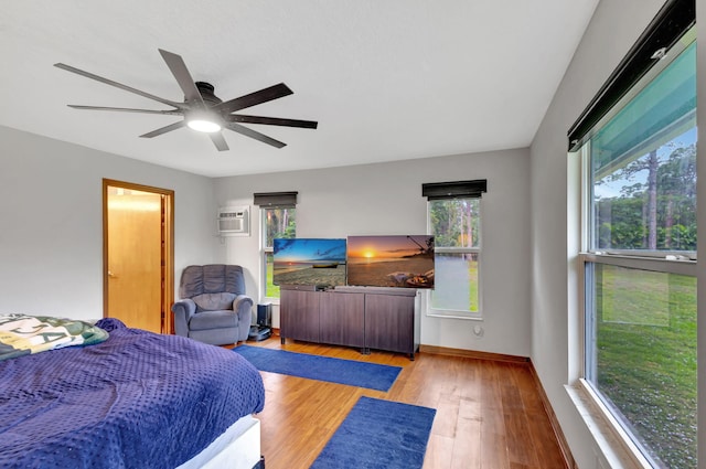 bedroom featuring ceiling fan, a wall mounted AC, and light hardwood / wood-style floors