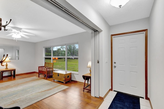 foyer entrance featuring ceiling fan, a textured ceiling, and light hardwood / wood-style flooring