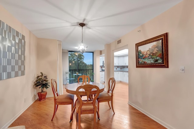 dining area with a wall of windows, light hardwood / wood-style flooring, and an inviting chandelier