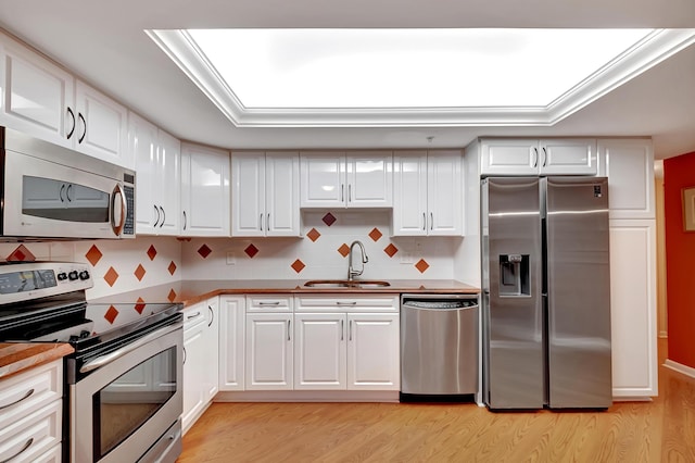 kitchen featuring white cabinetry, stainless steel appliances, decorative backsplash, sink, and light hardwood / wood-style floors