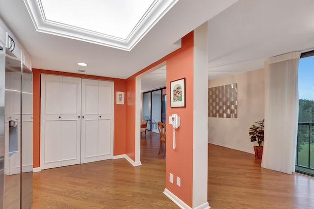 hallway with a skylight and light hardwood / wood-style floors