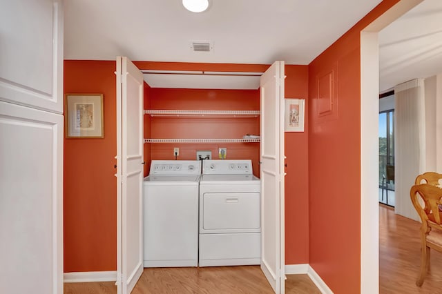 laundry area featuring washer and clothes dryer and light hardwood / wood-style flooring