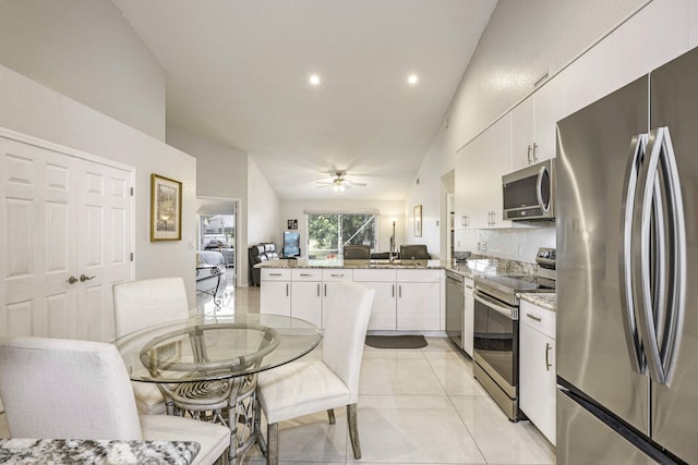 kitchen featuring kitchen peninsula, white cabinetry, vaulted ceiling, and appliances with stainless steel finishes