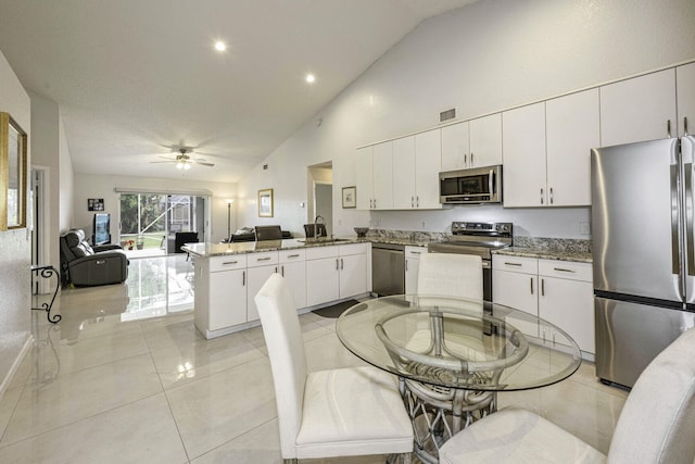 kitchen featuring white cabinets, sink, kitchen peninsula, stainless steel appliances, and stone countertops