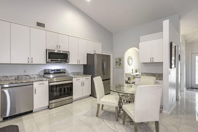 kitchen featuring light stone counters, white cabinets, light tile patterned flooring, and appliances with stainless steel finishes